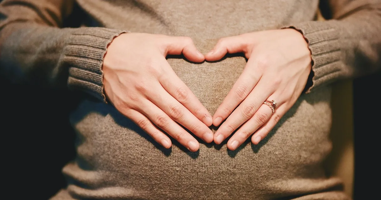 Gravidez após bariátrica: gestante com as mãos em forma de coração sobre a barriga